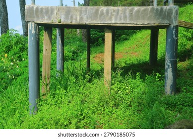 Concrete Platform Structure with Pillar Support on Green Grassy Hill. Small Elevated Viewpoint Foundation in Forest Park, Rural Construction Development and Infrastructure Landscape Photography