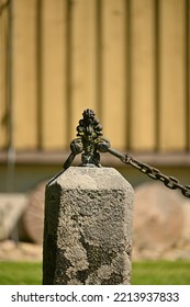 A Concrete Rectangular Fence Post And A Metal Chain From It