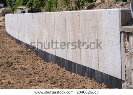 A concrete retaining wall protecting the slope against landslides.Redevelopment of a city street. Newly built retaining wall . Newly built retaining wall. Construction work at the construction site . 