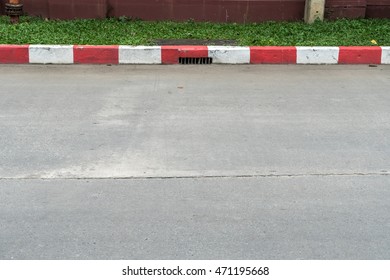 Concrete Road With Red And White Curb And Green Grass Sidewalk