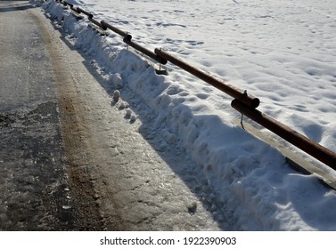 concrete roadblock used on the highway between two lanes and driving directions connected by wooden poles in the shape of a mobile railing that will not allow cars to park in the snow low fence