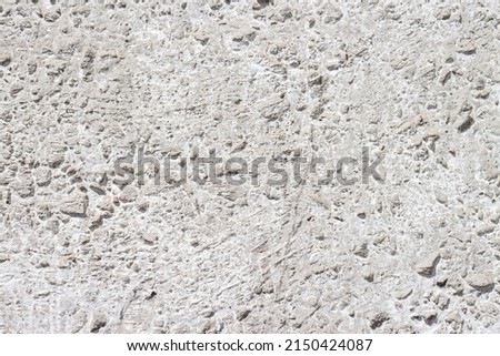 Concrete with rocks wall bumpy painted surface for cool urban grungy wallpaper or macro background