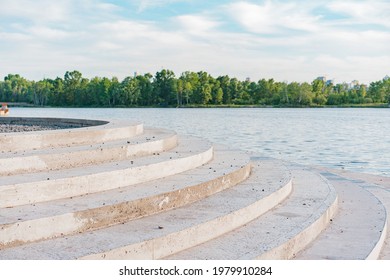 Concrete round steps going to the water. River. Lake. Sea. Recreation. Water. Nature. Trees. Green. Tranquility. Rounded. Urban