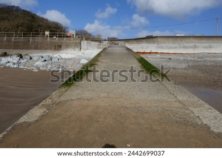 A concrete slipway leading from the seawall to the sandy beach at Amroth, Pembrokeshire, Wales, UK.
