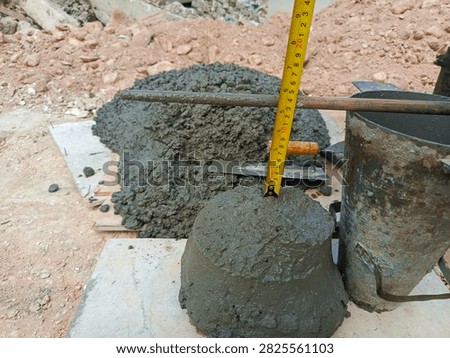 Concrete slump test in progress at construction site. Measuring workability of fresh concrete with slump cone and tape measure. Quality control check before foundation pouring. Essential concrete testing for builders, engineers and contractors ensuring structural strength. Learn proper slump measurement technique for your building project.