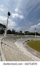 The Concrete Stadium Arena Of Stadium Merdeka In Kuala Lumpur, Malaysia With Its Towering Floodlight Against A Blue Cloudy Sky.