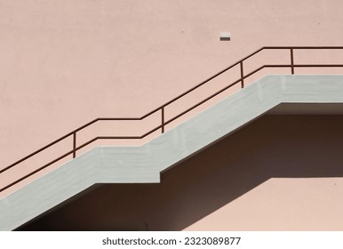 Concrete staircase with brown metallic railing on pink painted facade. Background for copy space.