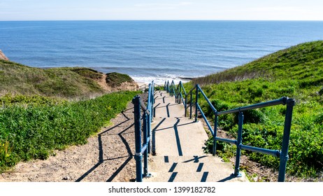 Concrete Stairs Leading Down To Seaham Hall Beach In County Durham, England UK.  Image Taken On A Warm Sunny Day Showing A Calm North Sea, Grass Hills Either Side And A Blue Sky.