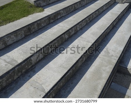 concrete stairs to the park serving at the same time as a sitting bench. gray cement clean smooth bright cement surface. granite cubes paving threshing gravel road. overgrown with plants. anti-slip