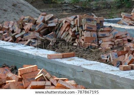 Concrete strip foundation and brick heaps prepared for a cottage building