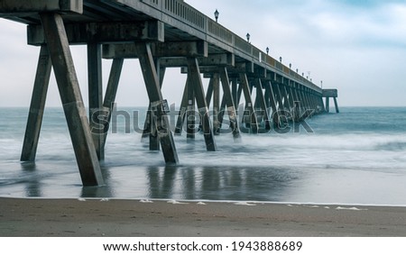 The concrete supports of Johnnie Mercer's Pier create rigid intersecting angles. The long exposure of the photograph smooths out the contours of the waves. 