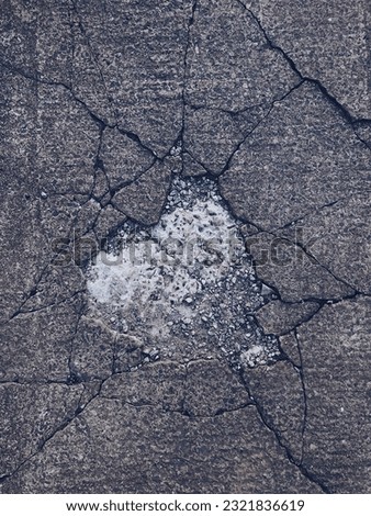 Concrete surface with cracks and potholes as background texture