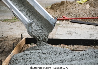 Concrete Truck Chute Pouring Wet Cement Mix into a Form with Reinforcing Bar for a Sidewalk
