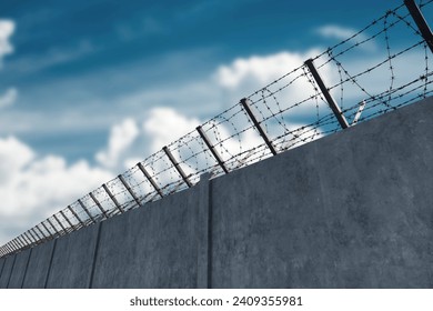 Concrete wall with barbed wire against blue sky. Concept border, prisons, refugees, loneliness. mixed media, copy space - Powered by Shutterstock