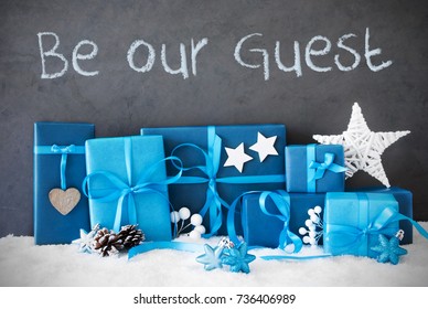 Concrete Wall With English Text Be Our Guest. Blue Christmas Gifts With Decoration Like Stars And Fir Cone On Snow.