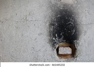 Concrete Wall On The Exterior Of A Pottery Kiln With Black Soot Charred Mark Coming From The Opening, Which Is Filled With A Brick.