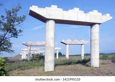 Concrete white bridge supports. Construction of a road bridge between the cities. Poles and pillars for the bridge among the field against the sky.