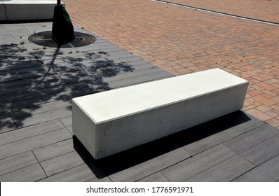 Concrete White Park Bench Block Shape On Dark Paving Square, Clean Cast Concrete Surface Gray Brown White Light Barrier Against Traffic Terrorism Pedestrian Zone