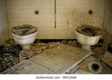 A condemned bathroom with dirty toilets in an abandoned building.