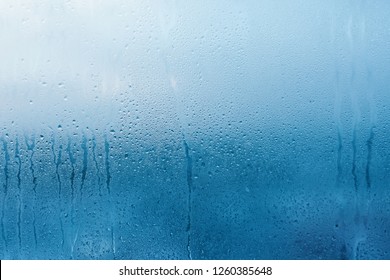 Kondensation auf dem klaren Glasfenster. Wasser fällt. Regen. Abstrakte Hintergrundtextur