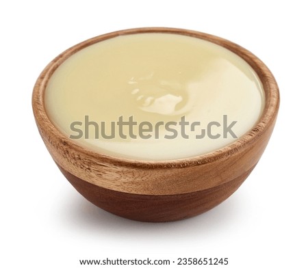 condensed milk in wooden bowl isolated on white background