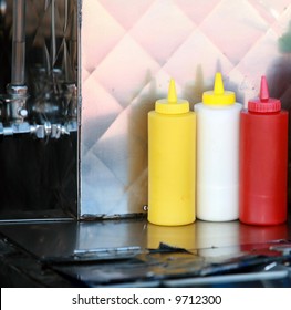 condiments of mustard, mayonnaise, ketchup and hot sauce on a hot dog cart for your use - Powered by Shutterstock