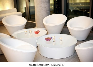 Condo Party Room With White Modern Seats And Low Tables With Bowl Of Nuts And Candles.