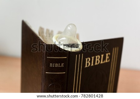 Condom, having sex and birth control vs Bible as religious book of Christianity and Christian religion (very low depth of field)