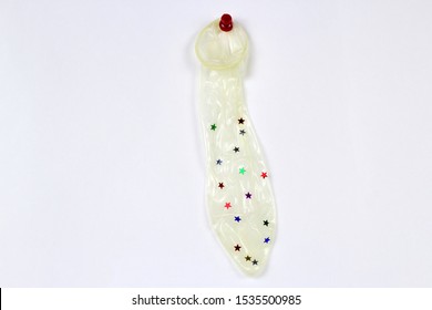 a condom pinned to a white wall with sequins stars,the concept of safe sex and prevention of STDs