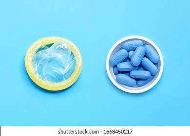 Condom With PrEP ( Pre-Exposure Prophylaxis) Used To Prevent HIV, In Plastic Pill Bottle Cap On Blue Background.  Safe Sex Concept. 