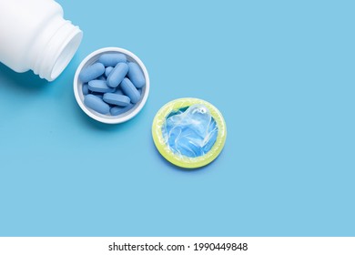 Condom With PrEP ( Pre-Exposure Prophylaxis) Used To Prevent HIV, In Plastic Pill Bottle Cap On Blue Background.  Safe Sex  Concept. 