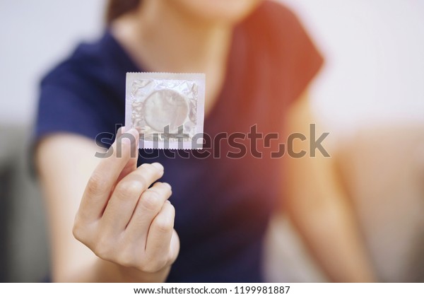 Condom ready to use in female hand, give condom\
safe sex concept on the bed Prevent infection and Contraceptives\
control the birth rate or safe prophylactic. World AIDS Day, Leave\
space for text.