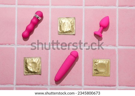 Condoms, butt plug and vibrators on a pink background