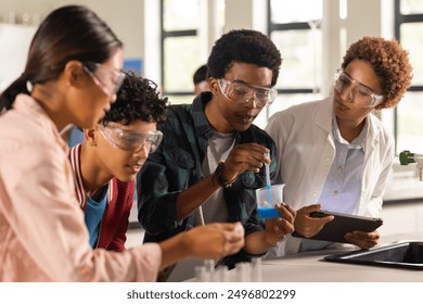 Conducting science experiment in high school, students with teacher supervising in classroom. Education, teaching, learning, supervision, chemistry, biology - Powered by Shutterstock