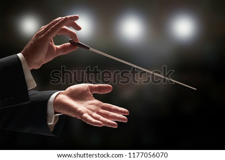 Conductor conducting an orchestra with audience in background