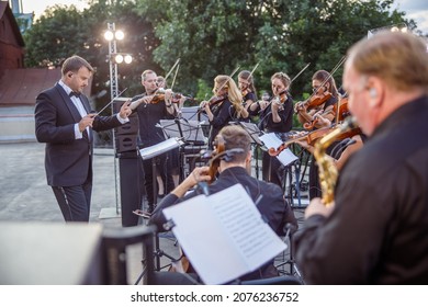 Conductor Directing Orchestra Performance On Outdoor Stage