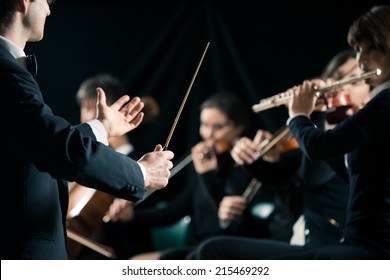 Conductor Directing Symphony Orchestra With Performers On Background.
