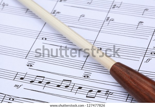 Conductor\'s baton and music\
score.