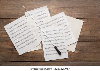 Conductor's baton and sheet music on wooden table, flat lay - Powered by Shutterstock