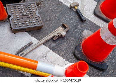 Cone Closed Off Street Area With Un-covered Underground Gas Line, Working With Tools Mallet And Pipe Wrench