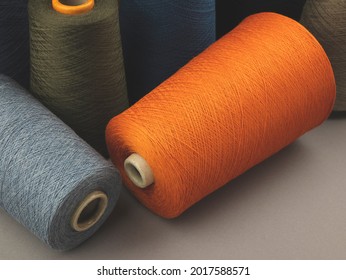 Cones of colored cotton, woolen or synthetic threads. Bobbins of yarn using in textile manufacturing and for handmade products, copy space