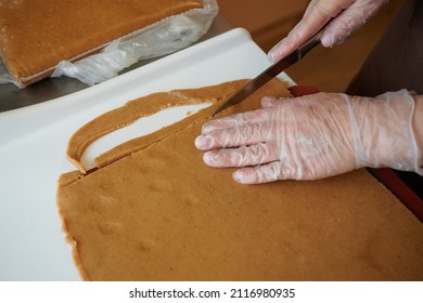 A Confectioner Cuts Strips Of Gingerbread Dough With A Kitchen Knife On His Work Table. Manual Preparation. Technology For Making Treats