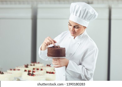 Confectioner decorating chocolate cake in pastry shop.