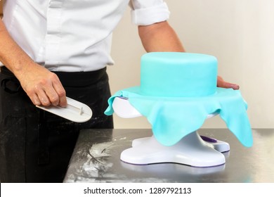 Confectioner Decorating A Wedding Cake With Blue Fondant .