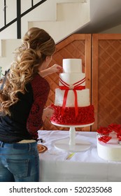 Confectioner Decorating A Wedding Cake With Edible Red Marzipan Flowers