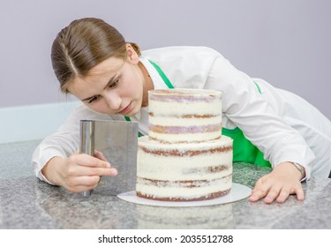 confectioner makes a wedding cake with white cream  using a  cooking spatula