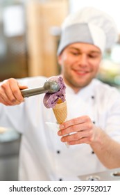 Confectioner putting ice cream to the waffle cone in the pastry shop