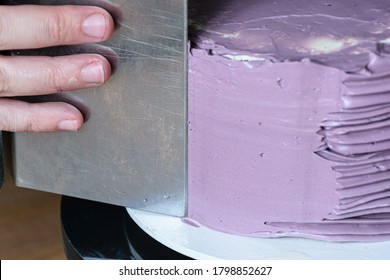 Confectioner Using Bench Scraper To Finish The Cake.