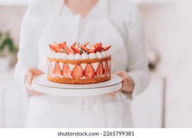 Confectioner in white uniform holding strawberry mousse cake. - Powered by Shutterstock