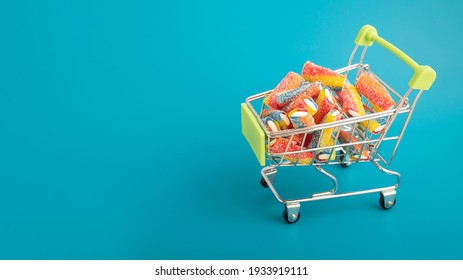 Confectionery and desserts, Sweet candy toffee multicolored in a basket cart on a blue background with copy space - Shutterstock ID 1933919111